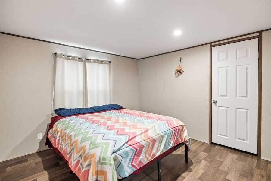 Room featuring wood-finish flooring, recessed lighting, and a paneled interior door Room featuring wood-finish flooring, recessed lighting, and a paneled interior door