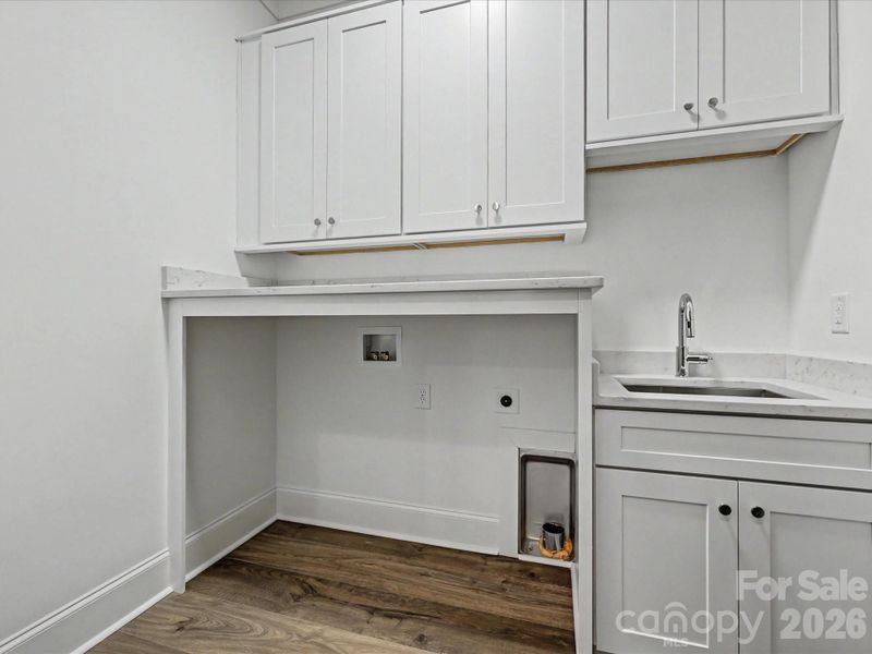 Well-appointed laundry room with built-in cabinetry, utility sink, and ample counter space for added functionality and storage.