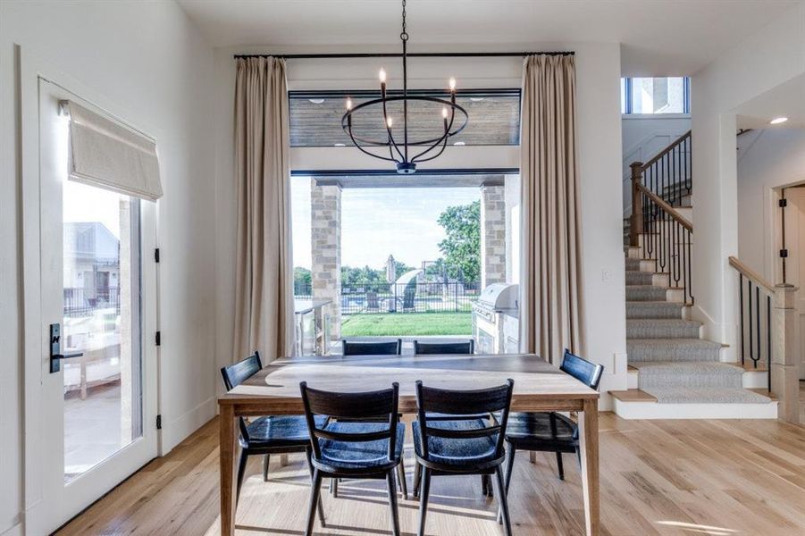 Dining space featuring light wood-type flooring, stairs, and a chandelier Dining space featuring light wood-type flooring, stairs, and a chandelier