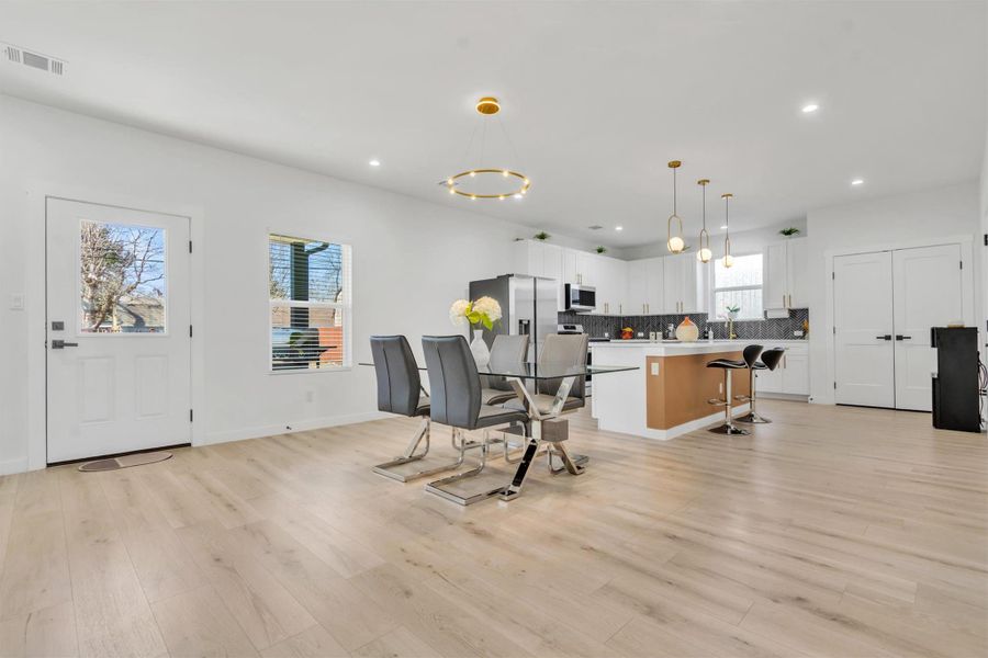 Kitchen with a breakfast bar area, white cabinetry, a kitchen island, pendant lighting, and light wood finished floors