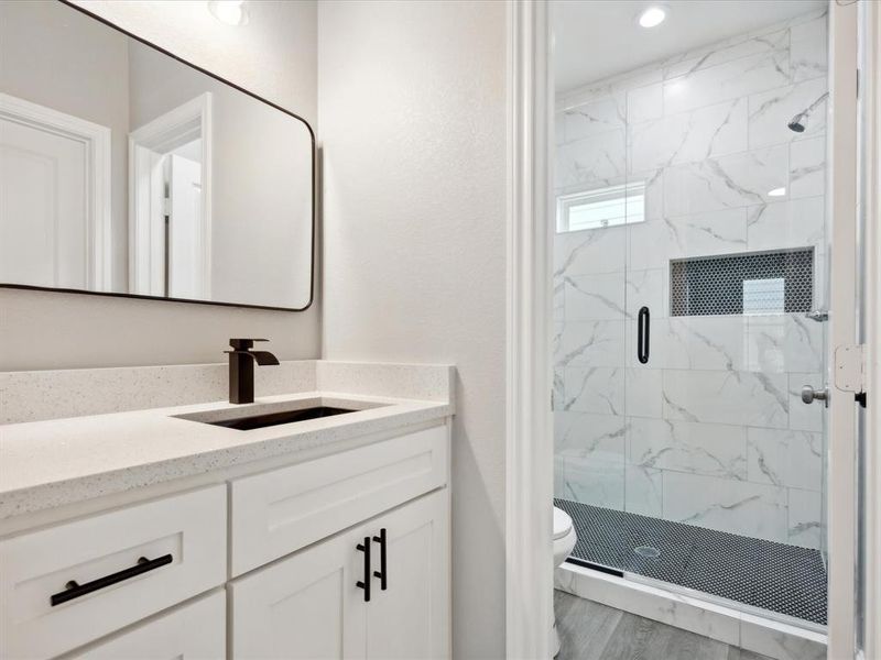 Bathroom with a shower with shower door, vanity, toilet, and wood-type flooring