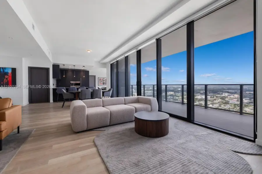 Floor-to-ceiling glass windows, expansive private balcony, wood-finish flooring, and integrated cabinetry