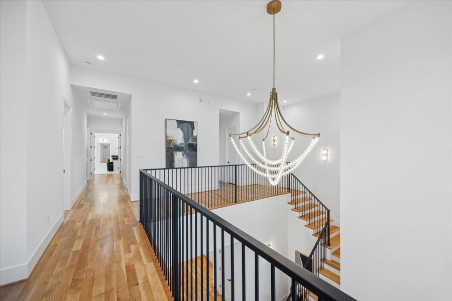 An open upstairs landing functions as a central connector between bedrooms while maintaining visual connection to the main level below. Wide plank floors, modern railing, and statement lighting keep the space feeling open and usable rather than purely transitional. An open upstairs landing functions as a central connector between bedrooms while maintaining visual connection to the main level below. Wide plank floors, modern railing, and statement lighting keep the space feeling open and usable rather than purely transitional.
