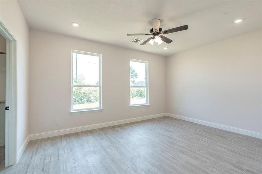 Empty room with ceiling fan and light wood-type flooring