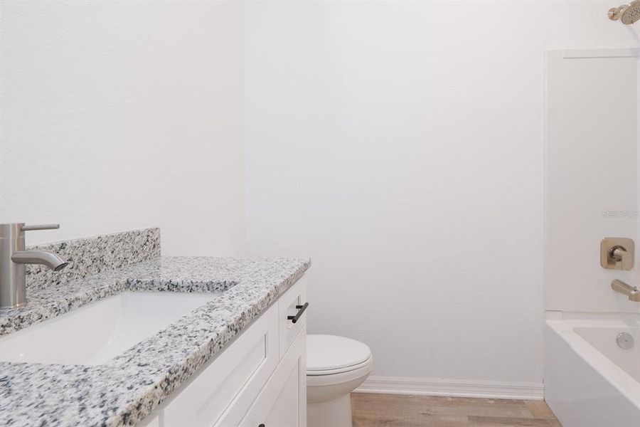 Guest bathroom with tub, granite countertops