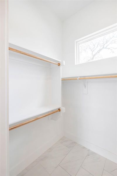 Walk in closet with light marble finish flooring