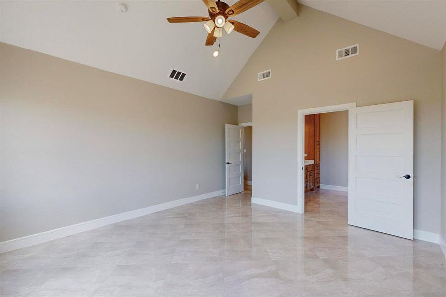 Unfurnished bedroom with light tile patterned floors, beamed ceiling, high vaulted ceiling, and ceiling fan