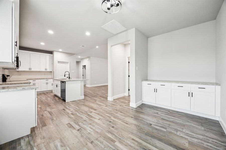 Breakfast area of Kitchen has buffet cabinet with a kitchen island with sink white cabinets, granite countertops, Stainless steel appliances, light wood-style flooring, and recessed lighting