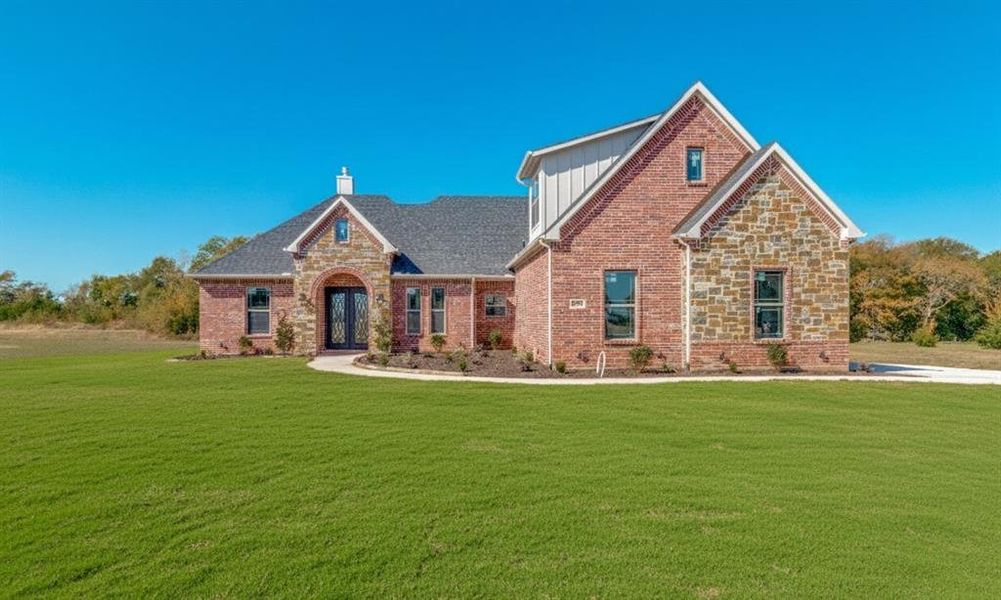 View of front of property featuring a front lawn, brick siding, and stone siding
