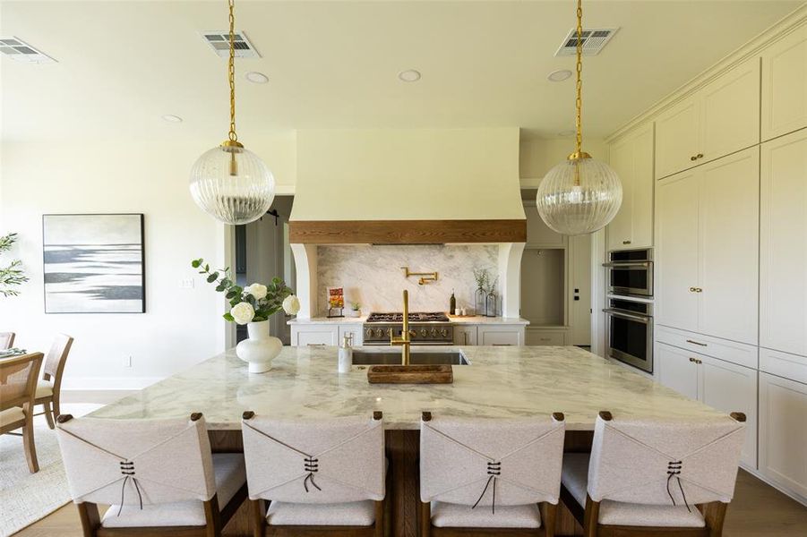 Spacious kitchen island featuring a stone countertop, integrated sink, and seating for four