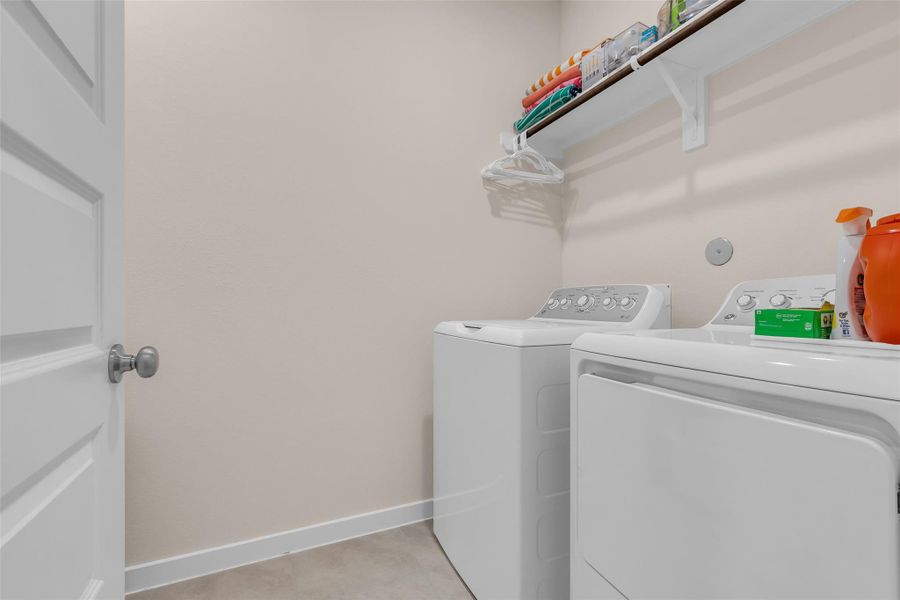This is a compact, well-lit laundry room with a washer and dryer. It features wall shelving for storage and a light neutral color palette, creating a clean and efficient space. This is a compact, well-lit laundry room with a washer and dryer. It features wall shelving for storage and a light neutral color palette, creating a clean and efficient space.