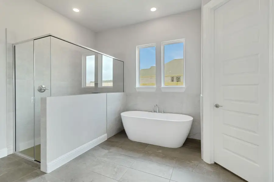 Bathroom featuring recessed lighting, a freestanding bath, a stall shower, and tile walls