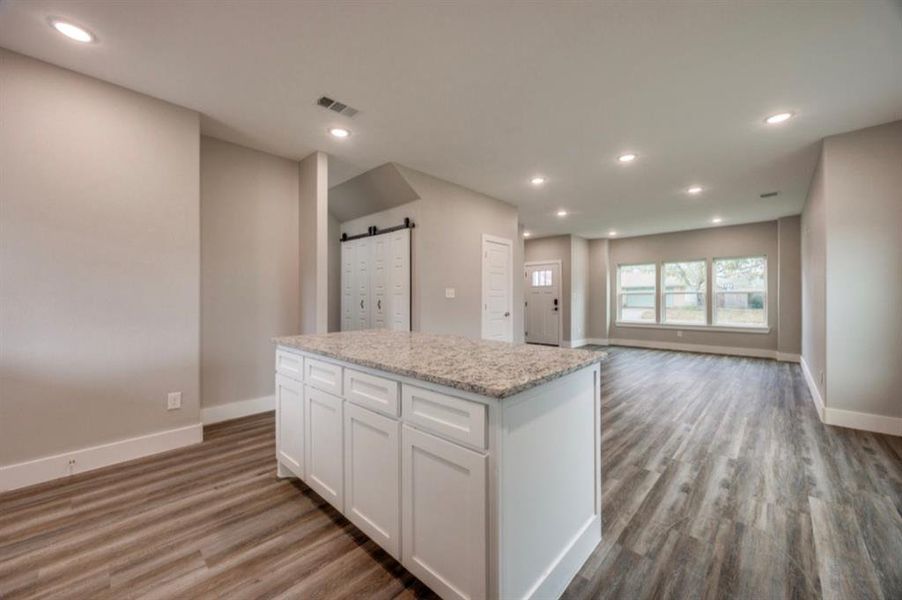 Kitchen with white cabinetry, a barn door, a kitchen island, recessed lighting, and light wood-type flooring