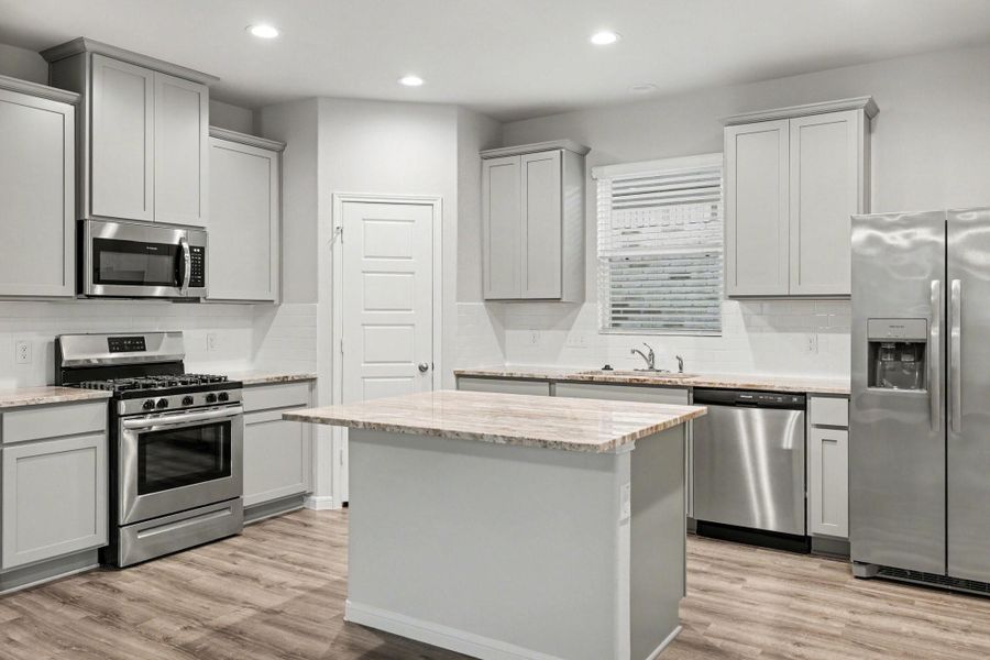 Kitchen with island workspace, double sink, and window bringing in natural light. Kitchen with island workspace, double sink, and window bringing in natural light.
