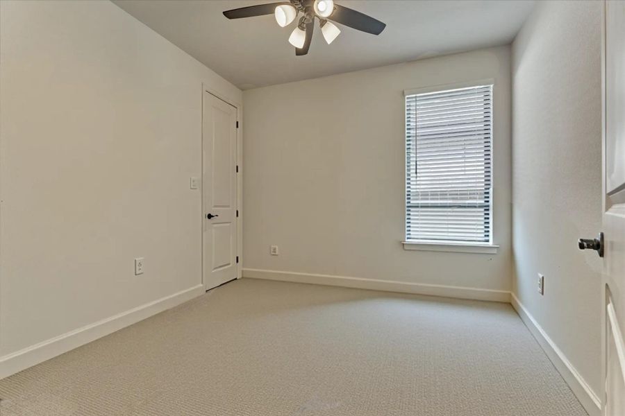 This inviting secondary room(2) offers a bright, versatile space with fresh carpeting, a modern ceiling fan, and abundant natural light—perfect for a guest room.