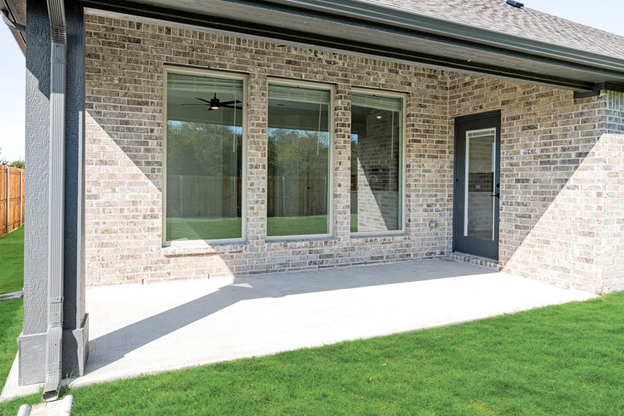 Covered back patio with concrete slab, brick exterior, large windows, and back door entry to home Covered back patio with concrete slab, brick exterior, large windows, and back door entry to home