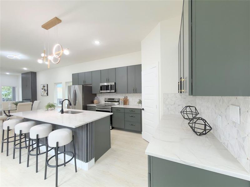 Kitchen featuring a kitchen breakfast bar, a kitchen island with sink, light stone counters, decorative light fixtures, and tasteful backsplash