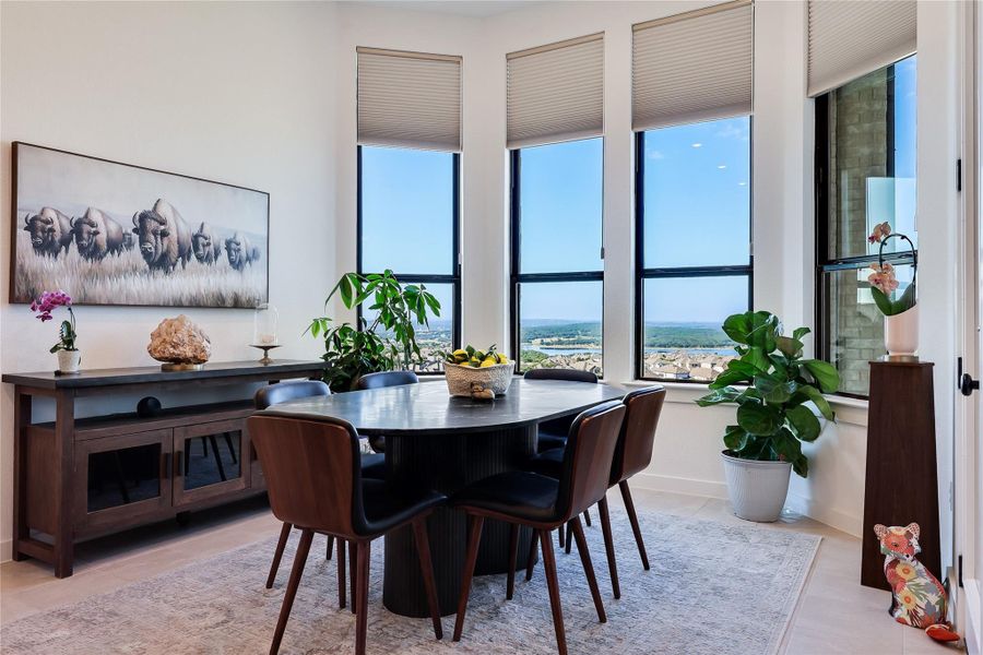 Towering windows frame distant water and hillside views in this modern dining area. Towering windows frame distant water and hillside views in this modern dining area.