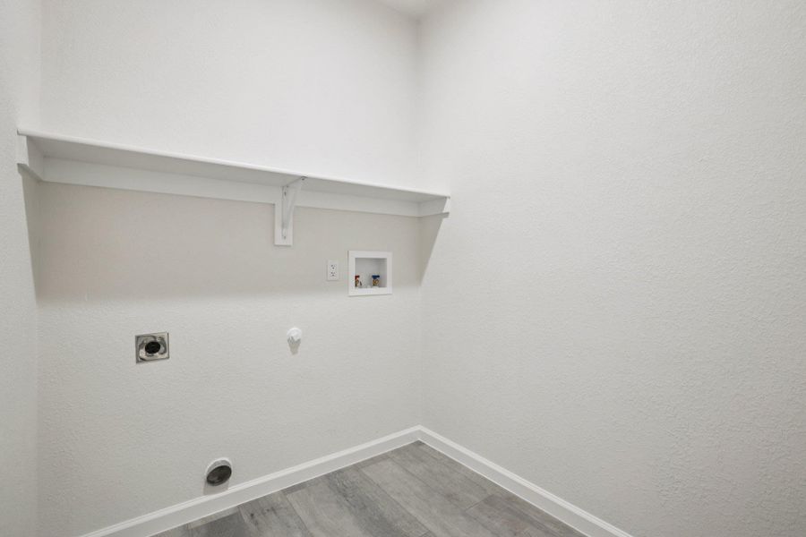 Laundry area with gas dryer hookup, light wood-type laminate flooring, hookup for a washing machine, electric dryer hookup, and a textured wall