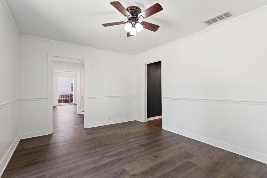 Empty room with ceiling fan, dark wood-style floors, baseboards, and ornamental molding