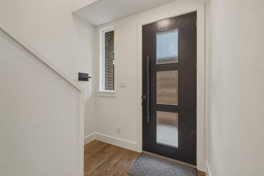 Foyer entrance featuring dark wood-type flooring and baseboards