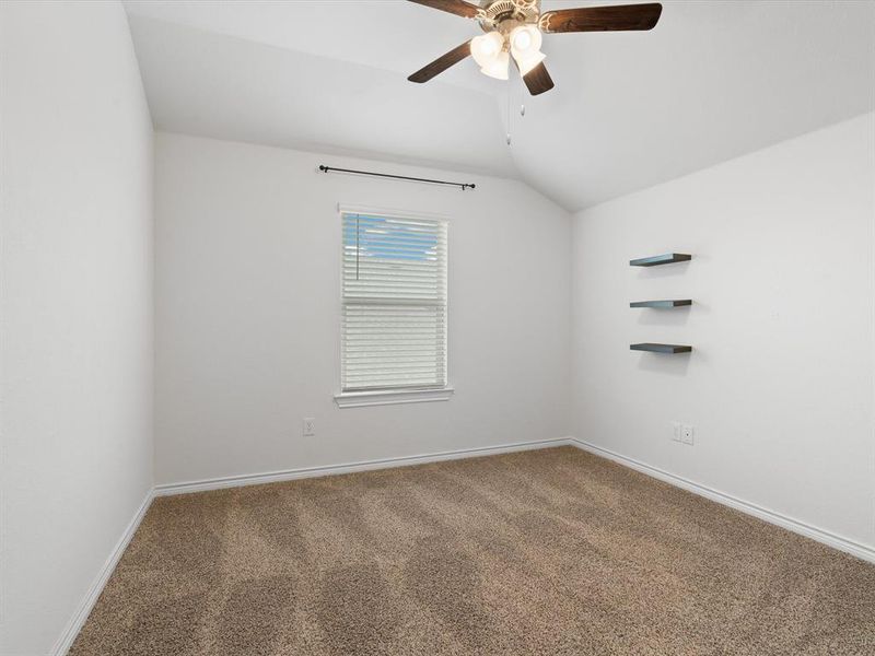 Carpeted spare room with vaulted ceiling and ceiling fan