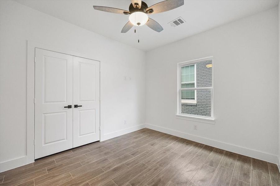Unfurnished bedroom with wood finish floors, a ceiling fan, and a closet