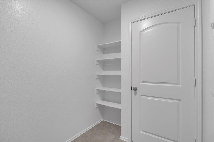 This is a great, neutrally painted storage space featuring built-in shelves on one wall for extra laundry storage.