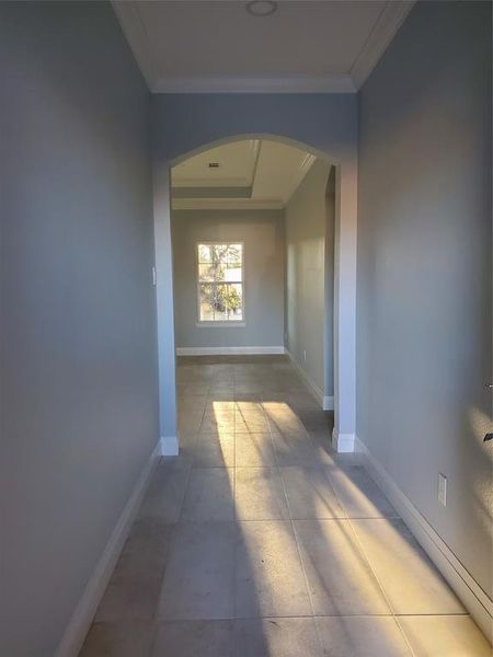 Hall featuring light tile patterned flooring and crown molding