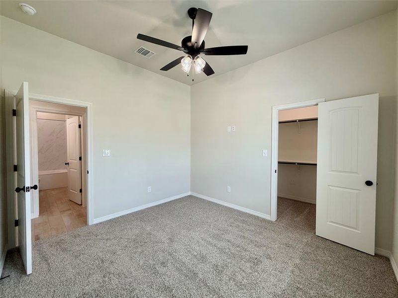Unfurnished bedroom with carpet floors, a spacious closet, a closet, and ceiling fan