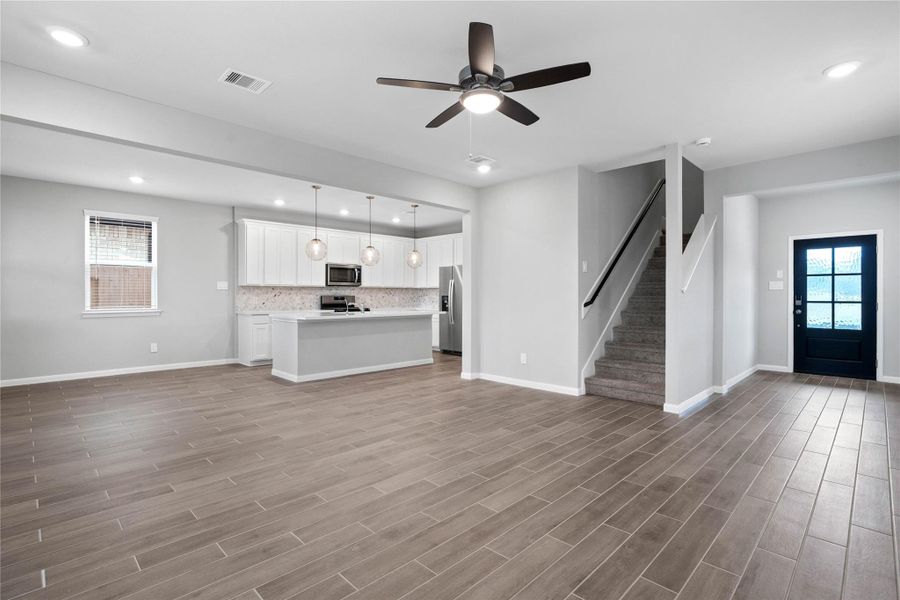This expansive view from Great Room showcases a seamless, open-concept layout that creates a warm and inviting path for guests, drawing the eye toward the welcoming front entryway
