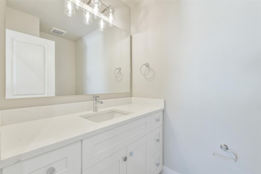 Convenient half bath located just off the living area leading to the secondary bedrooms, featuring a clean modern vanity and updated fixtures.