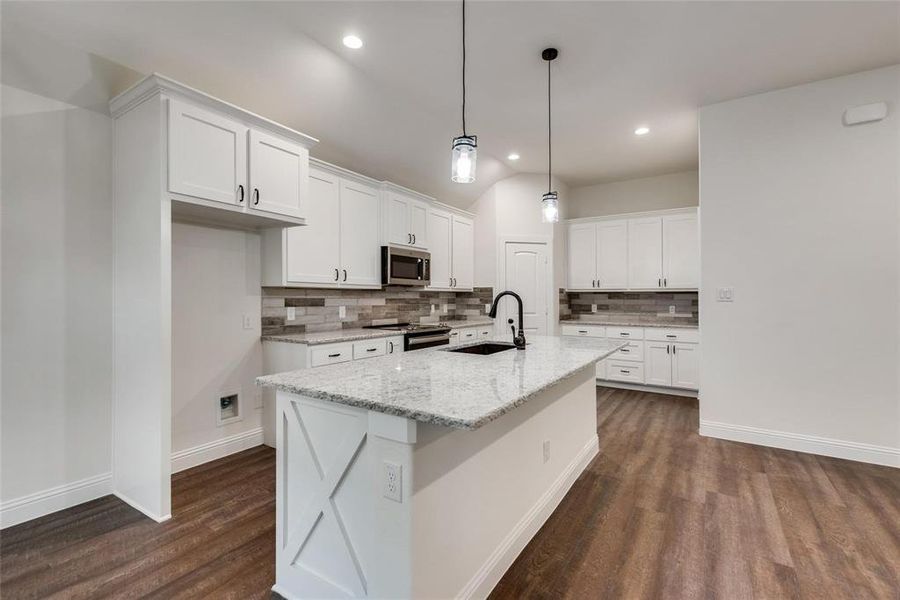 Kitchen featuring white cabinets, tasteful backsplash, light stone counters, dark wood-style floors, and lofted ceiling