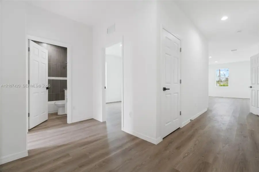 Interior space featuring wood-finish flooring, recessed lighting, and multi-panel interior doors with matte black hardware Interior space featuring wood-finish flooring, recessed lighting, and multi-panel interior doors with matte black hardware