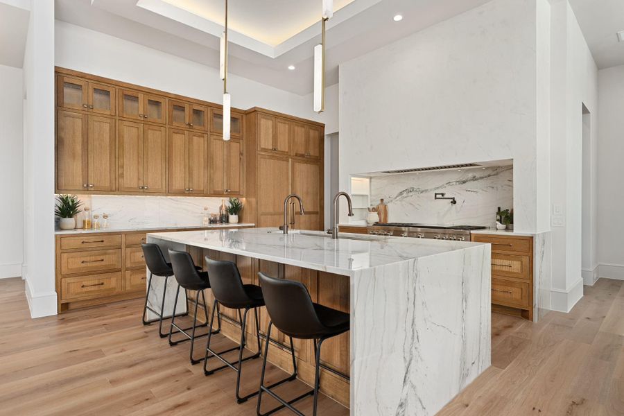 Sleek kitchen with natural wood cabinetry and a generously sized marble island, perfect for entertaining.