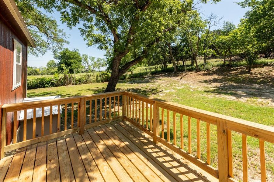 Outdoor wooden deck with natural wood railing overlooking a verdant landscape