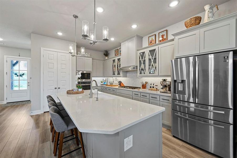 Kitchen with appliances with stainless steel finishes, a chandelier, recessed lighting, light countertops, and glass insert cabinets Kitchen with appliances with stainless steel finishes, a chandelier, recessed lighting, light countertops, and glass insert cabinets