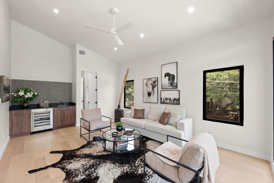 A refined entertaining space features a wet bar, sleek wine cooler, and light hardwood floors. A refined entertaining space features a wet bar, sleek wine cooler, and light hardwood floors.
