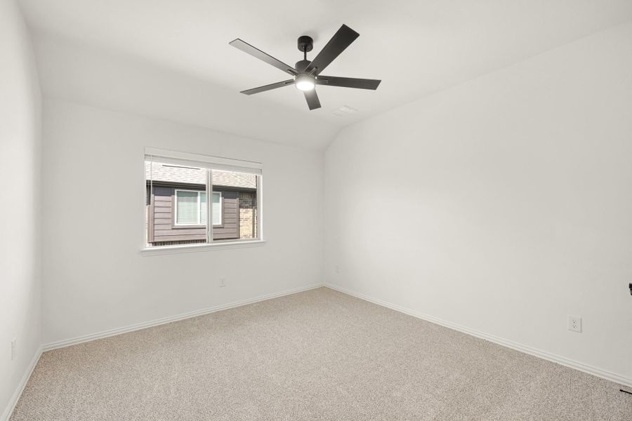 Empty bedroom with vaulted ceiling, black ceiling fan, carpet flooring, and single window