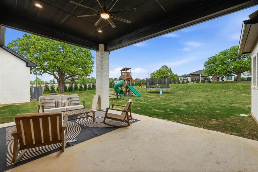 View of patio featuring a trampoline, outdoor seating, a playground, and a ceiling fan