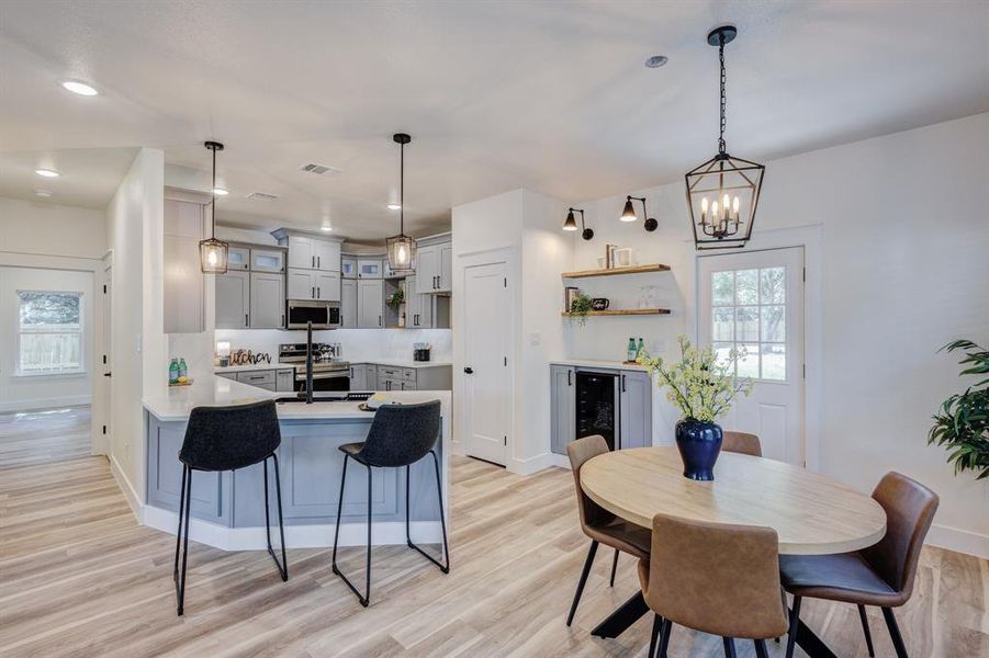 Kitchen with hanging light fixtures, kitchen peninsula, gray cabinetry, appliances with stainless steel finishes, and light wood-type flooring