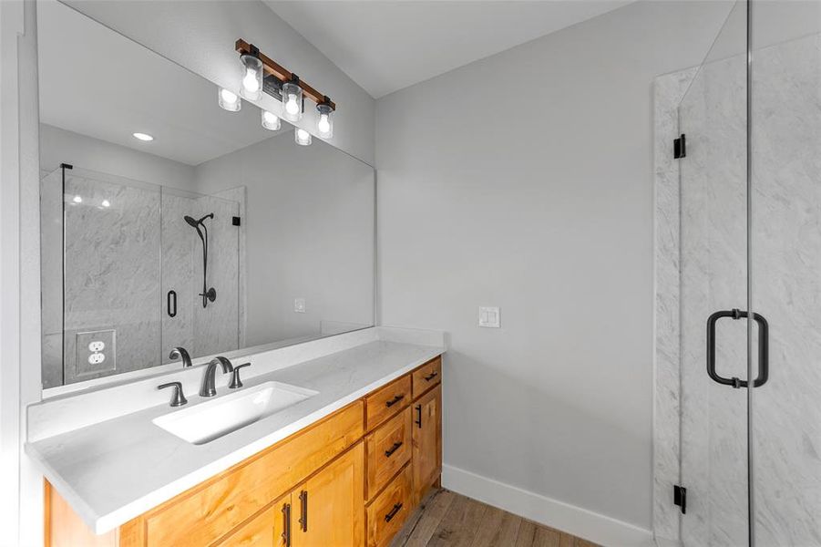 Bathroom with vanity, an enclosed shower, and wood-type flooring