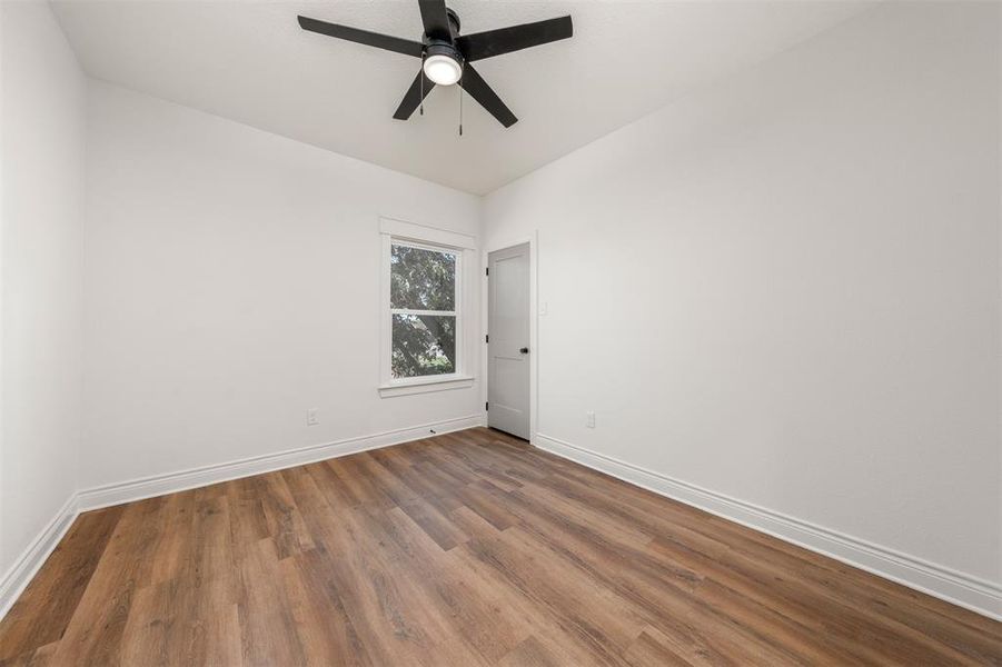 Empty room with wood finished floors and a ceiling fan Empty room with wood finished floors and a ceiling fan