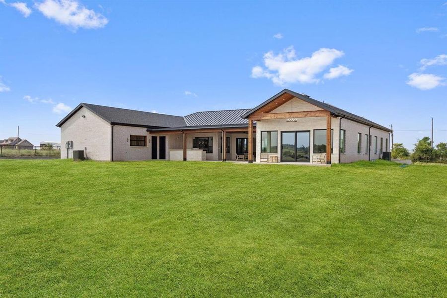 Rear view of property with a patio, a lawn, a
standing seam roof, and a metal roof Rear view of property with a patio, a lawn, a
standing seam roof, and a metal roof