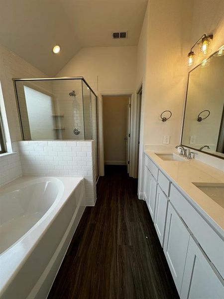 Bathroom featuring plus walk in shower, vanity, lofted ceiling, and hardwood / wood-style flooring