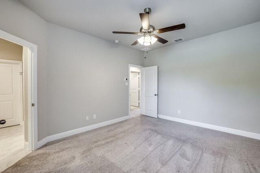 Empty room with a ceiling fan, carpet floors, and baseboards
