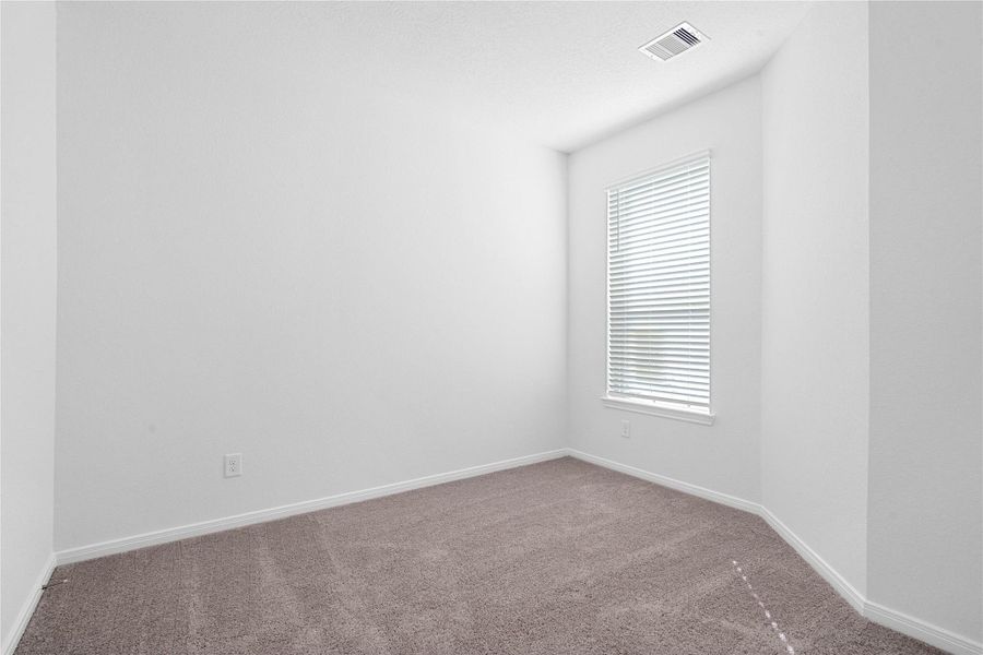 Tucked peacefully in the front of the home is this secondary bedroom. It features custom paint, a large window with fitted blinds, and a generously sized closet.