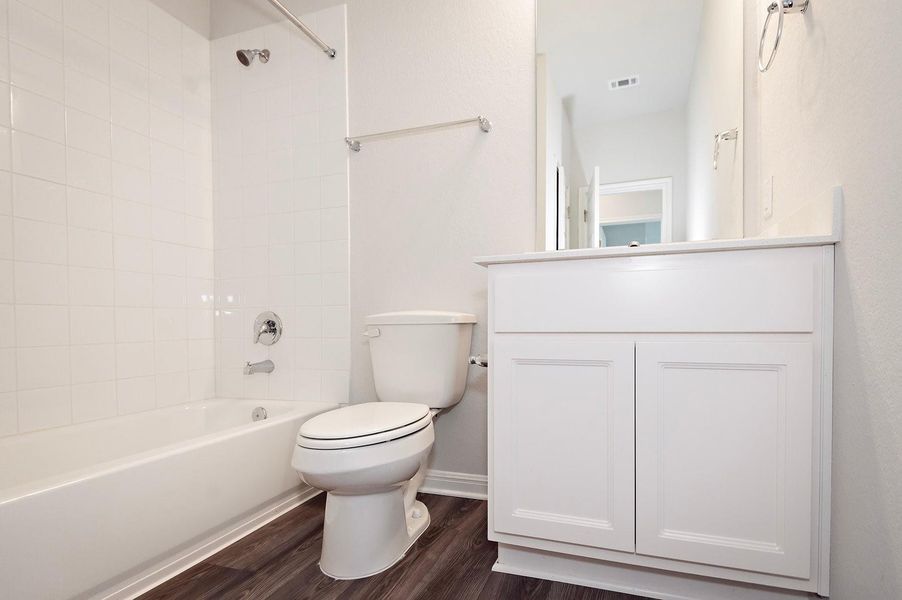 Full bathroom featuring toilet, wood finished floors, shower / bathtub combination, vanity, and baseboards Full bathroom featuring toilet, wood finished floors, shower / bathtub combination, vanity, and baseboards