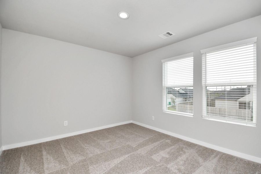 Secondary bedroom features plush carpeting, large windows that let in plenty of natural light, bright paint, and spacious closets. Sample photo of completed home with similar floor plan. Actual colors and selections may vary.