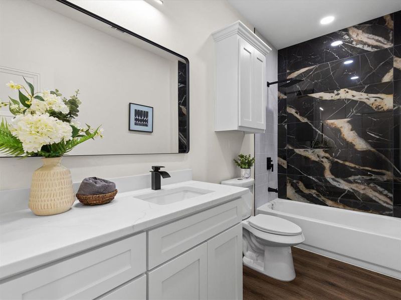 Bathroom featuring vanity, shower / washtub combination, and dark wood-type flooring